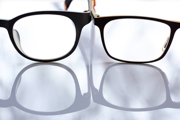 Dos anteojos miopes o miopes sobre fondo de mesa acrílico blanco, Primer plano y plano macro, enfoque selectivo, reflexión, concepto óptico
 - Foto, Imagen