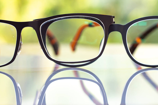 Due occhiali da vista miopi o miopi neri su tavolo acrilico bianco, sfondo del giardino verde Bokeh, Close up & Macro shot, Focus selettivo, Riflessione, Concetto ottico
 - Foto, immagini
