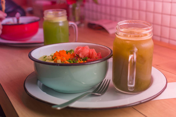 Alimentación sana y limpia: salmón, verduras y frutas en un recipiente con una bebida verde en un jarro de vidrio. Dieta bruta - Foto, imagen