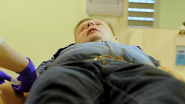 Медсестра делает внутривенную инъекцию человеку в джинсовом костюме
 - Кадры, видео