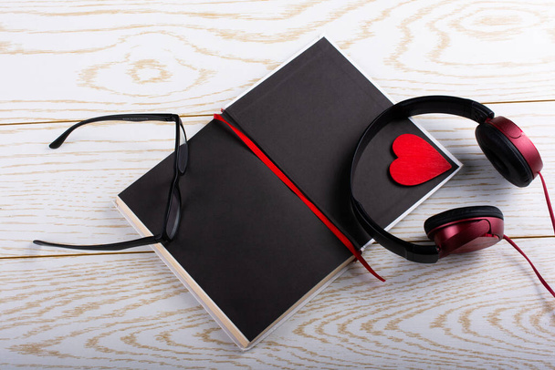 Ακουστικά, σημειωματάριο, στυλό, γυαλιά και καρδιά σε ξύλινο φόντο - Φωτογραφία, εικόνα