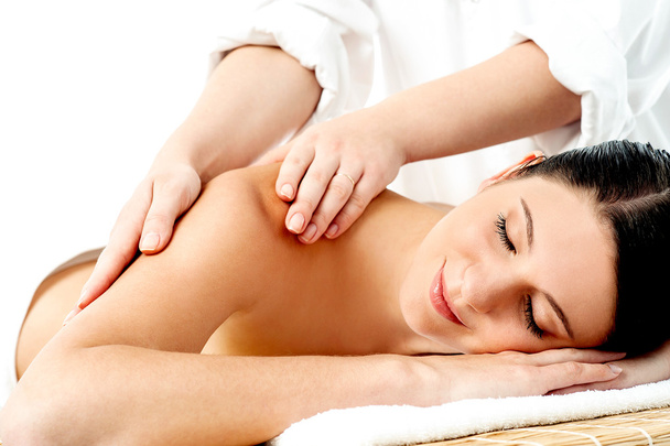 Relaxed young woman enjoying body massage - 写真・画像