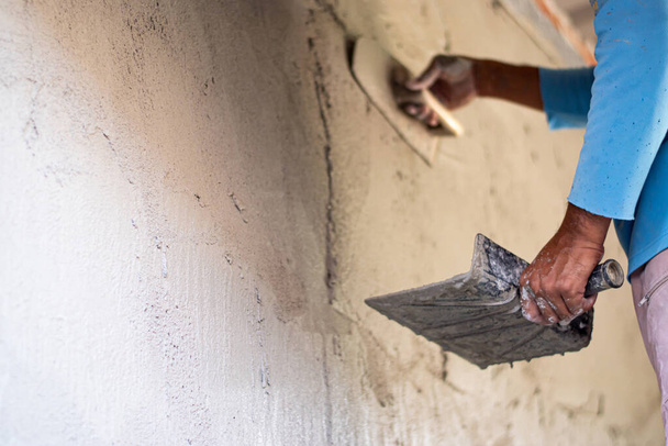 İnşaat işçileri duvarları sıva aletleriyle kaplamak için çimentoyu alçılıyorlar.. - Fotoğraf, Görsel