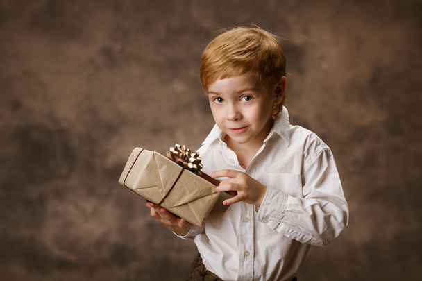 Child holding gift box. Vintage style. - Фото, изображение