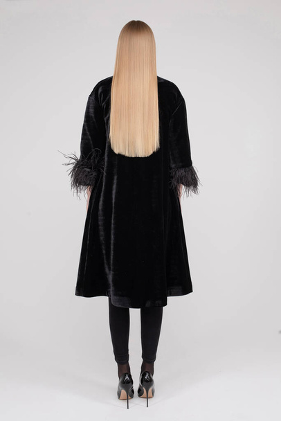 Back view full length fashion female model standing in black clothing having perfect healthy hair - 写真・画像