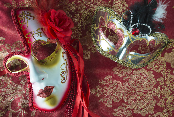 Zwei wunderschöne venezianische Karnevalsmasken auf wunderschönem Rot und Gold - Foto, Bild