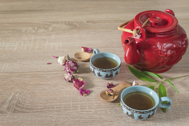 Teaidő-koncepció. Vörös teáskanna, két kínai csésze tea, rózsabimbó.  - Fotó, kép