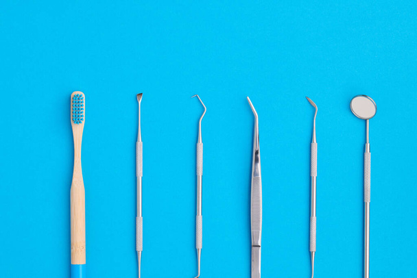 Οδοντιατρικά εργαλεία πάνω από μπλε φόντο πάνω όψη επίπεδη lay. Οδοντιατρική περίθαλψη, οδοντιατρική υγιεινή και υγεία.  - Φωτογραφία, εικόνα