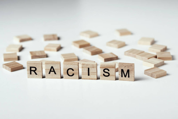 Pojęcie rasizmu i nieporozumień między ludźmi, uprzedzeń i dyskryminacji. Drewniany blok ze słowem rasizm na białym tle - Zdjęcie, obraz