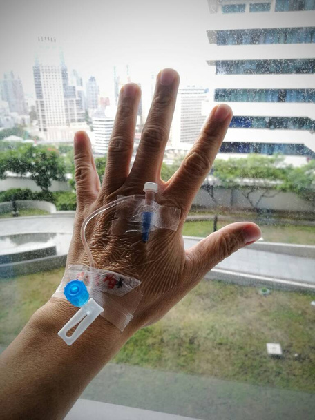 Medical dropper supplies the medicine through a needle directly into the vein of a person in the hospital.  Medical dropper sticked in the hands for survery case. - Photo, Image