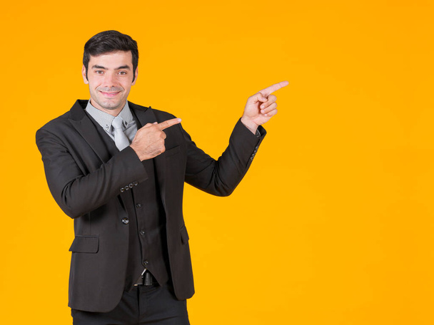 Ein junger Geschäftsmann in grauem Hemd und schwarzem Anzug zeigt mit beiden Fingern in die gleiche Richtung. Zeigt das Projekt, das derzeit im Höhenflug begriffen ist. Das Konzept der Investition in ein erfolgreiches Unternehmen. - Foto, Bild
