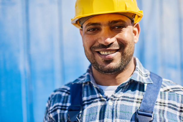 Smiling engineer in yellow construction helmet looks at the camera. - Photo, Image