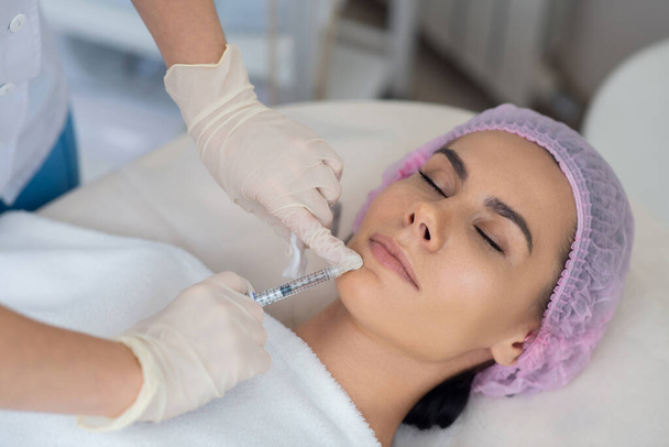 Dark-haired woman having beauty injections at the weekend - Foto, Bild