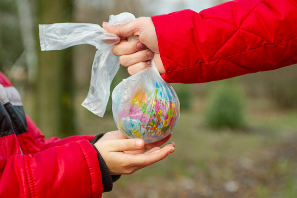 Hand of a little child reaching out to take a globe in plastic bag from an adult so he can take care of the earth for his future. Save the earth. World environmental day. - Photo, image
