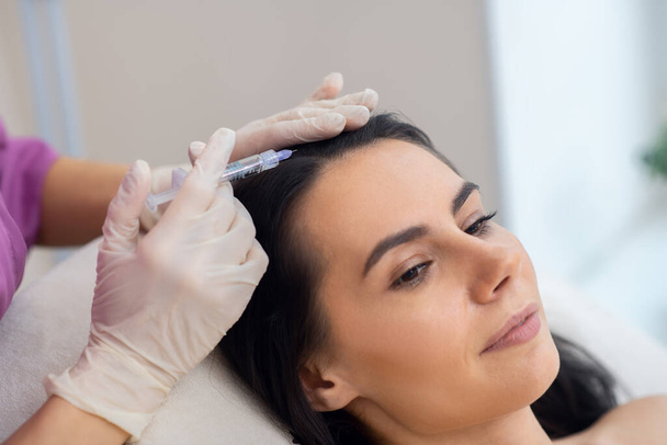 Dark-haired woman having injection to prevent hair loss - Foto, imagen