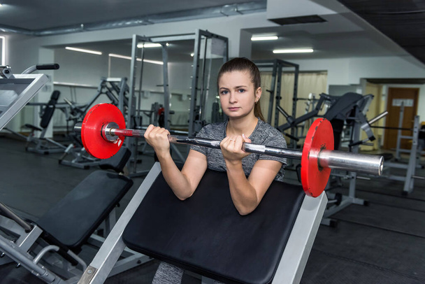 Jeune femme levant haltère dans la salle de gym
 - Photo, image