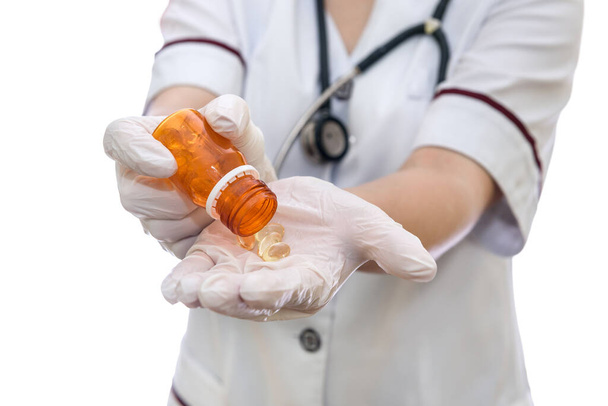 Arzthände in Handschuhen mit Flasche und gelben Kapseln - Foto, Bild