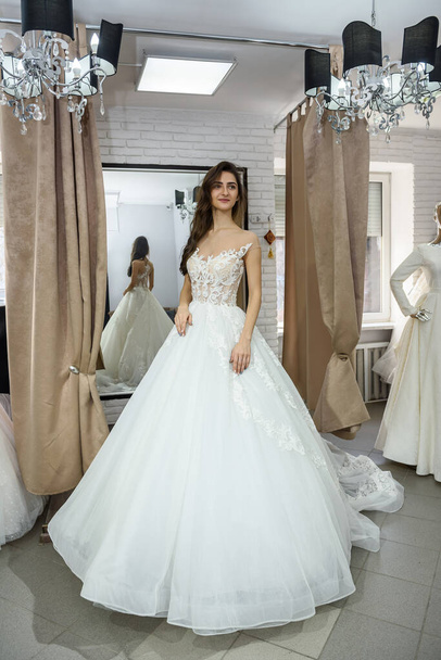 Усміхнена сукня нареченої у весільному салоні
 - Фото, зображення