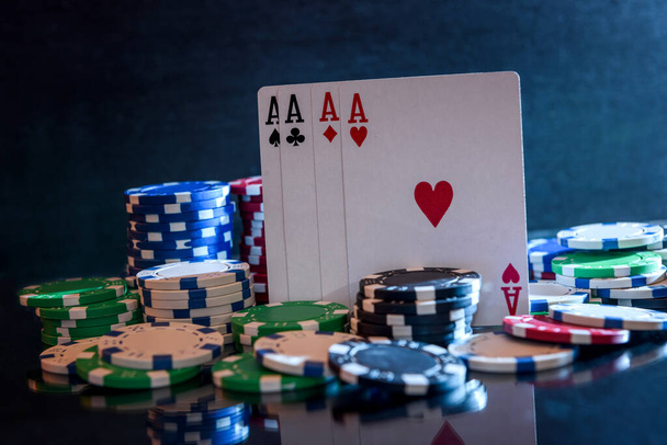 Jugar a las cartas con fichas de póquer en fondo negro
 - Foto, Imagen