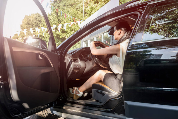 Mooie brunette poseren op bestuurdersstoel binnen auto - Foto, afbeelding