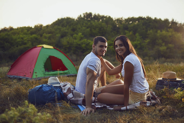 Romantic camping. A young couple sitting by the bonfire - Fotoğraf, Görsel