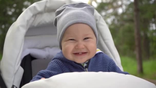 Egy bájos baba vidáman mosolyog egy babakocsiban ülve.. - Felvétel, videó