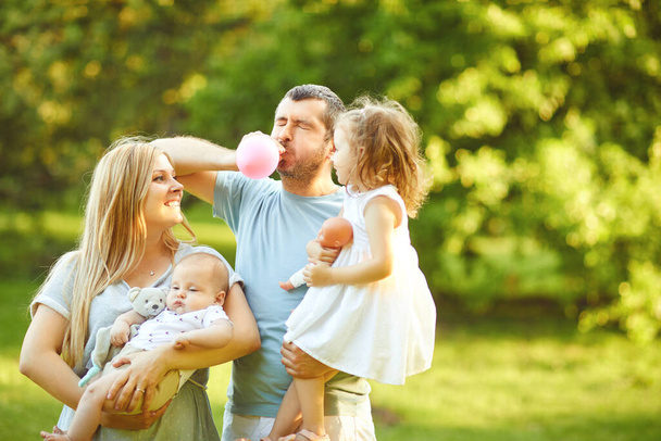 Family with baby stands on grass in the park - Foto, Imagem