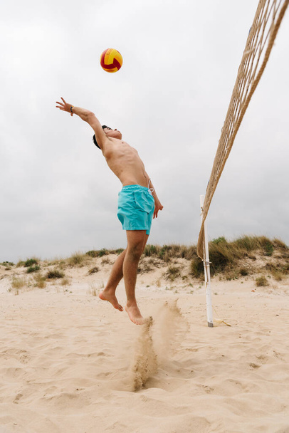 Young man playing volleyball on summer beach - Fotó, kép