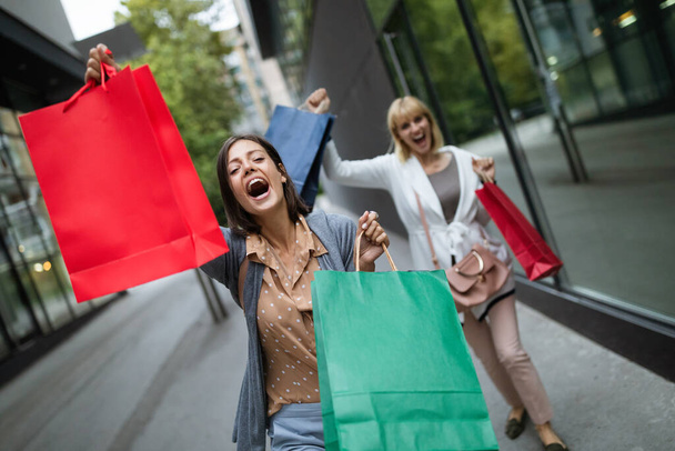 Shopping and tourism concept. Beautiful girls friends with shopping bags in ctiy - Фото, изображение