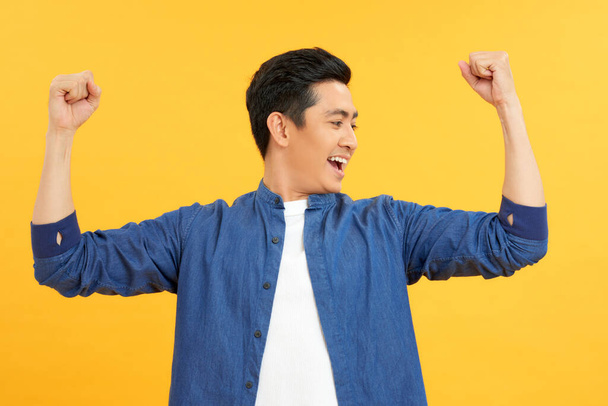 Successful man with arms up - isolated over a yellow background - Photo, Image