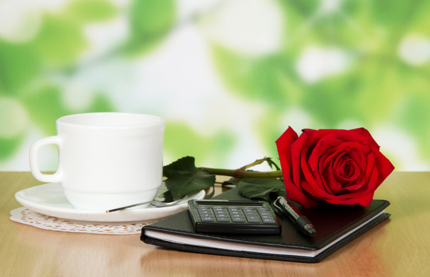 Table in cafe with a cup of coffee, rose and notebook - Foto, imagen