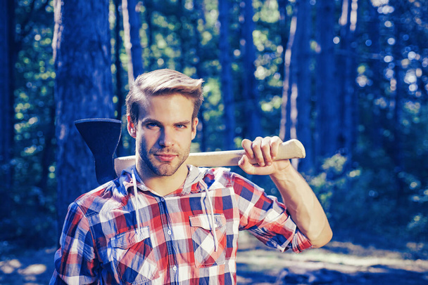 Lumberjack carries axe on shoulder. Deforestation. Handsome man with axe. Lumberjack in the woods with an ax. - Fotoğraf, Görsel