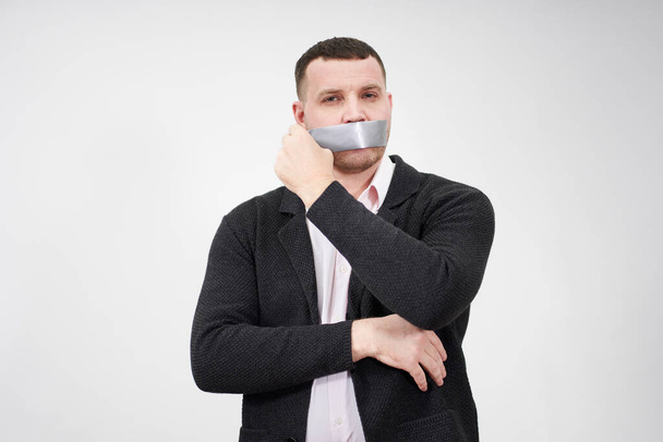 businessman is removing a piece of tape that has been covering his mouth - Foto, Imagen