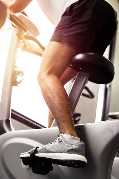 Fit man working out on exercise bike at the gym. Healthy and funny lifestyle concept. - Fotó, kép