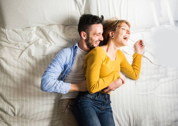 Two young adults at home - Beautiful happy couple of lovers having fun in bed - Fotoğraf, Görsel