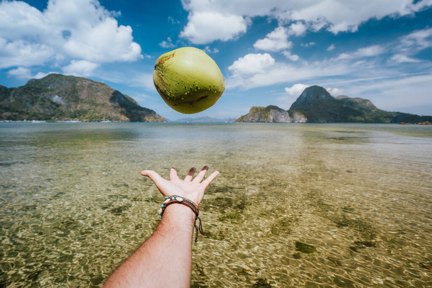 POV juggle with coconut in male hands against exotic islands in ocean bay - Foto, Imagem