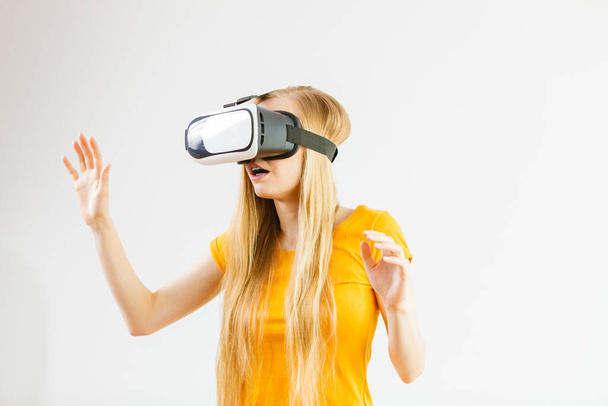 Young woman wearing virtual reality goggles headset, vr box, stretching arms. Connection, technology, new generation and progress concept. Studio shot on gray - Foto, immagini