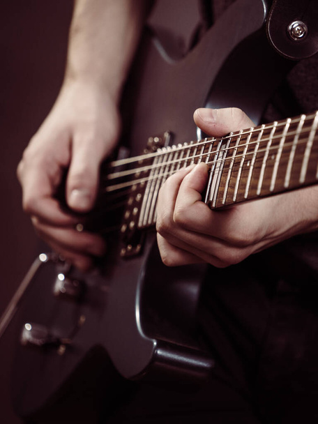 Male hands with electric guitar. Close up, part body adult person is holding instrument and playing. Hobby, music concept - Foto, imagen