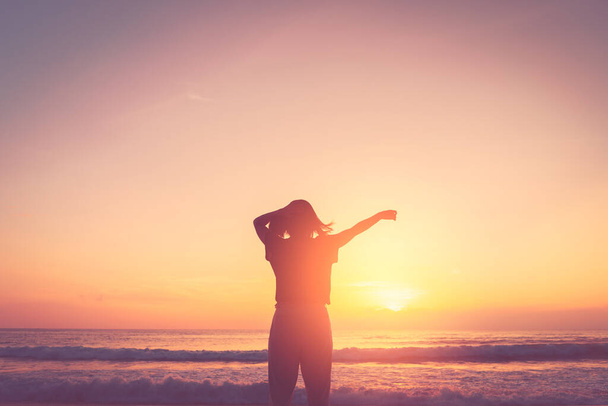 Copy space of woman rise hand up on sunset sky at beach and island background. Freedom and travel adventure concept. Vintage tone filter effect color style. - Photo, Image