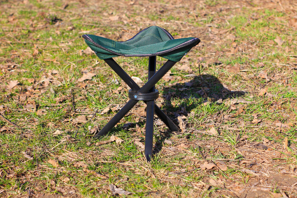Een campingstoel op groene natuur achtergrond. Picknick op een zonnig weer, familie dag rust, vakantie concept. Toeristische visserij-uitrusting voor avontuur, ontspannende winkel reclame banner.Copy ruimte, mockup - Foto, afbeelding
