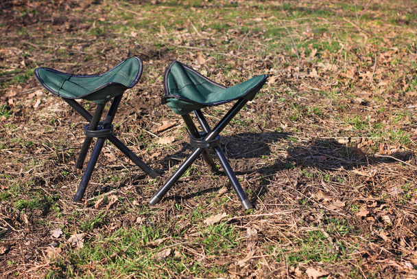 Dos sillas de campamento sobre fondo verde de la naturaleza. Picnic en un clima soleado, descanso familiar, concepto de vacaciones. Equipo turístico de la pesca para la aventura, banner publicitario relajante de la tienda. Espacio de copia, maqueta
 - Foto, imagen