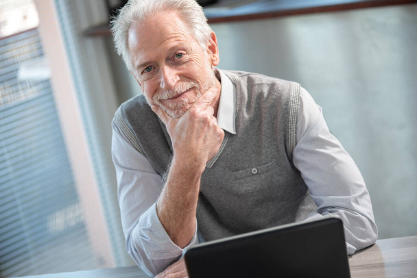 портрет улыбающегося старшего бизнесмена, сидящего в офисе
 - Фото, изображение