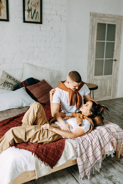 Beautiful couple on the bed. Love story in the interior Studio. Happy and laughing people. At home, having fun on the bed. - Foto, Bild