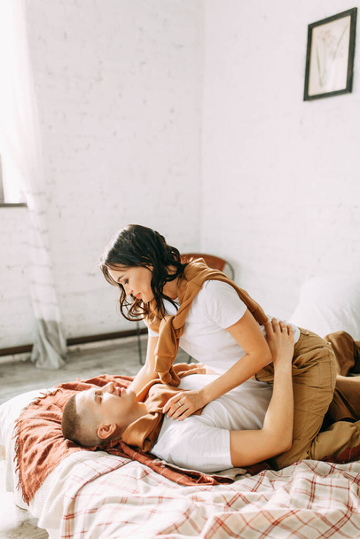 Beautiful couple on the bed. Love story in the interior Studio. Happy and laughing people. At home, having fun on the bed. - Foto, afbeelding