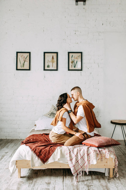 Beautiful couple on the bed. Love story in the interior Studio. Happy and laughing people. At home, having fun on the bed. - Zdjęcie, obraz
