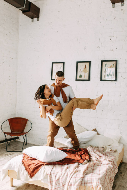 Beautiful couple on the bed. Love story in the interior Studio. Happy and laughing people. At home, having fun on the bed. - Foto, Imagen