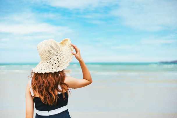 Happy Woman in summer vacation wearing hat and dress enjoying the view at the island beach. - 写真・画像