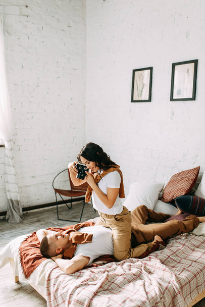 Love story in the interior Studio. They shoot each other on camera. The girl takes pictures of the guy on the bed.  - Foto, Bild