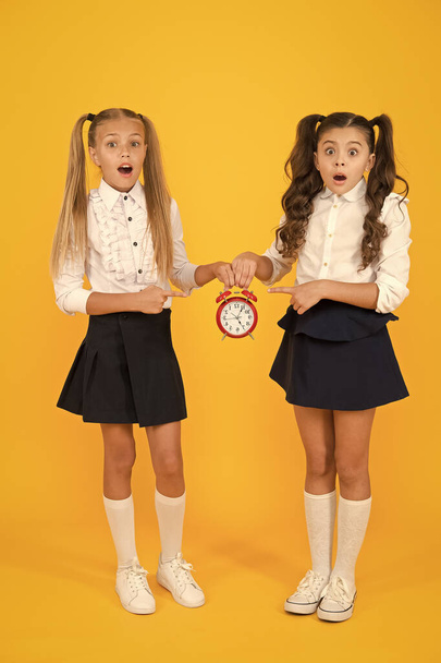 Primary school application deadline. Small children suffering from deadline stress on yellow background. Stressed little girl holding clock reminder of deadline. Deadline for submission - Fotoğraf, Görsel