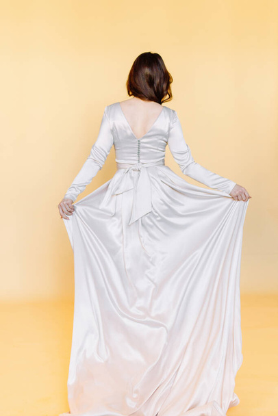Girl in a wedding dress. Minimalism at a wedding photo shoot. Beautiful bride in the Studio on a yellow background.  - Zdjęcie, obraz